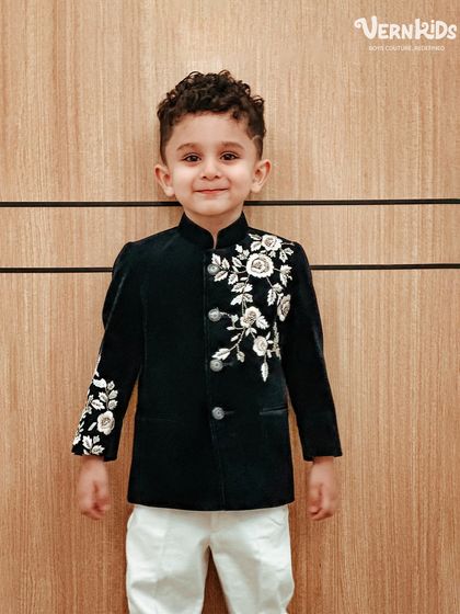 The smile says it all. This little client looks absolutely charming in our black velvet Indo-western jacket with delicate white floral embroidery.