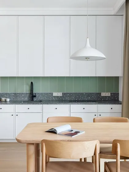 A minimalist kitchen design that combines natural wood-finish cabinets with clean white upper units. The terrazzo countertop and simple pendant light complete this Scandinavian-inspired look.