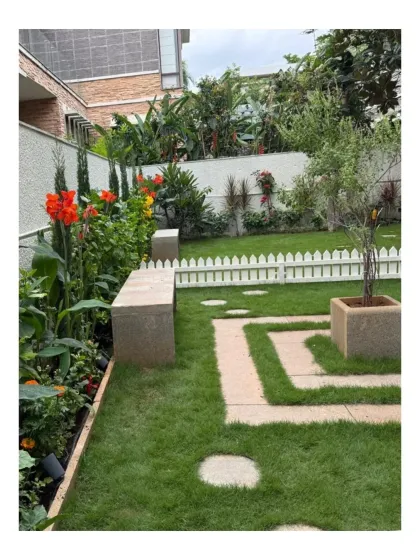 This residential garden at Chaithanya Samarpan features a formal lawn with geometric pathways and vibrant flower beds. The design balances structured elements with the softness of perennial flowers, creating a classic yet modern look.