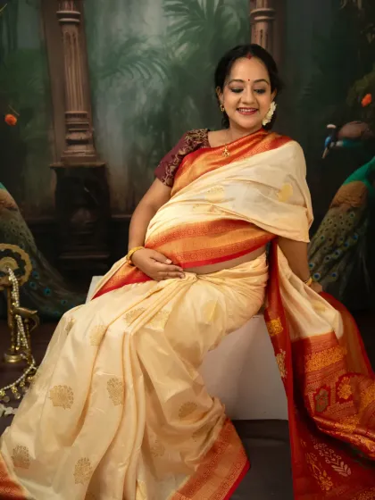 A joyful, candid moment captured during our traditional saree photoshoot. The mother-to-be's smile is infectious as she cradles her bump, seated elegantly in her beautiful attire.