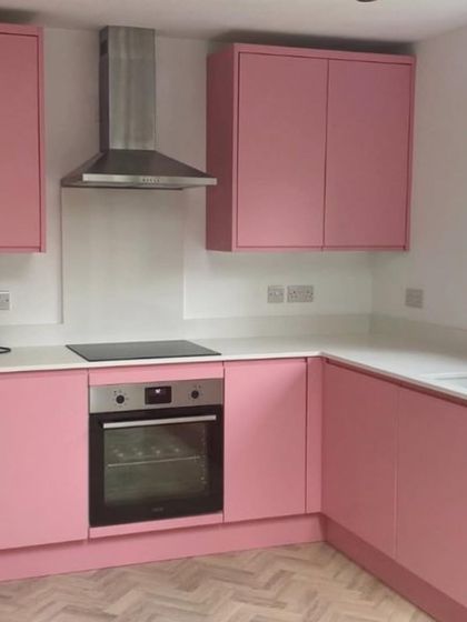 A simple yet charming L-shaped kitchen in a soft matte pink. Paired with a white countertop and herringbone wood-patterned flooring, this design is both trendy and timeless.