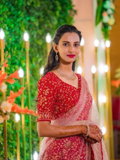 Posing by the floral decor, this client's makeup and hair look fresh and beautiful. The bright red lip stands out, and her simple hairstyle keeps the focus on her and her lovely attire.