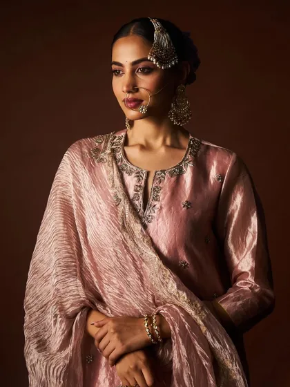A portrait of a model in the dusty rose sharara set, her hair adorned with a gajra, completing this look of classic Indian beauty.