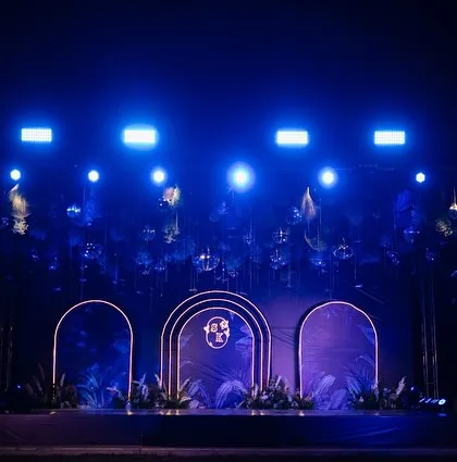 The Sangeet stage, ready for a night of performances. The clean, modern design with the couple's monogram and dramatic lighting set the scene for an unforgettable party.