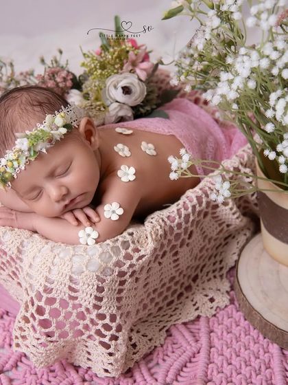 A little flower in full bloom. This baby girl, adorned with a floral headband and tiny blossoms on her back, looks like a true garden fairy.
