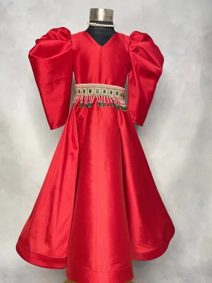 A regal red gown perfect for a Christmas party or a winter wedding. The puff sleeves and embellished belt add a touch of royal elegance to this festive piece.