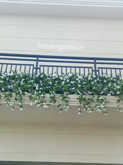 A close-up of a beautiful balcony railing planter, filled with white flowers and cascading greenery.