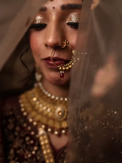 A beautiful, artistic shot of the bride through her veil. The glitter on her eyelids is still visible, adding a magical touch to this classic bridal portrait.