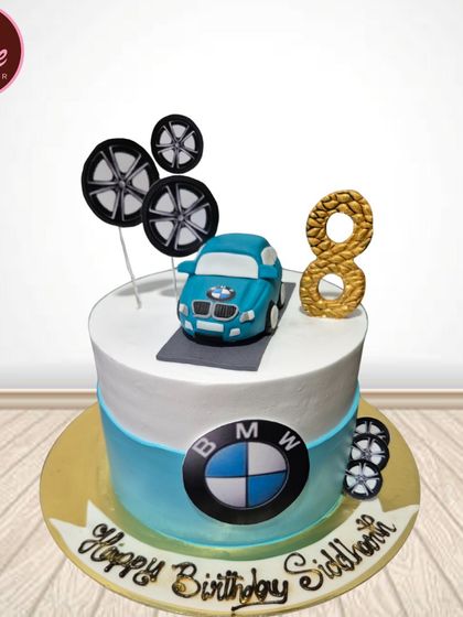 A sleek BMW-themed cake for a car lover's 8th birthday. The design includes the iconic logo, a fondant car topper, and edible wheel rims.
