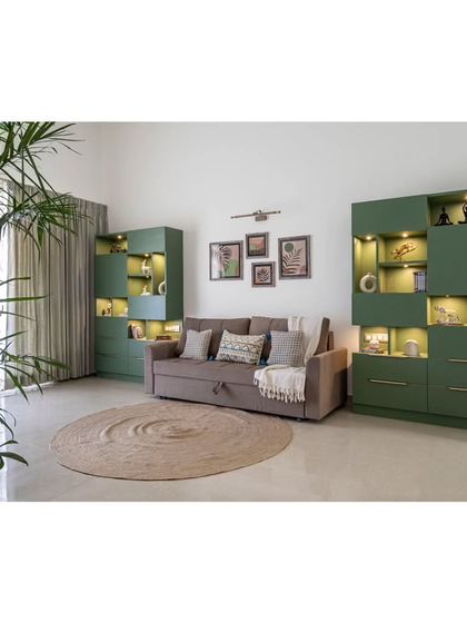 The home office/study room, featuring a versatile sofa-cum-bed flanked by striking olive green storage units. The space is designed to be multi-functional, serving as both a workspace and a guest area.