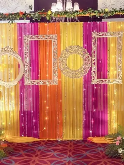 How do you make your mehendi ceremony pop? With a fun and colorful photo booth, of course. We created this backdrop using bright fabric drapes, ornate vintage frames, and delicate fairy lights, giving guests the perfect spot for memorable pictures.