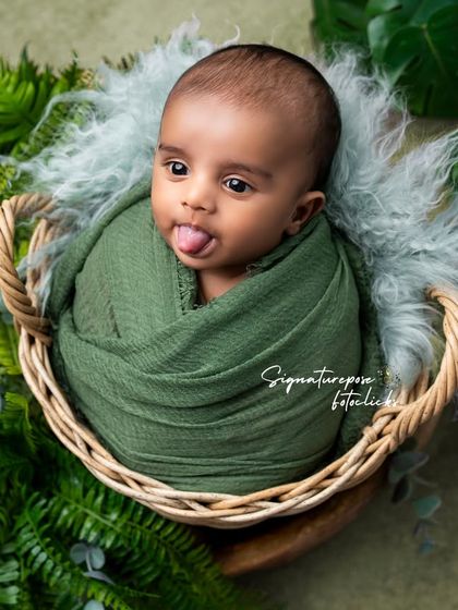 A playful newborn sticking his tongue out, a funny and candid moment from our nature-themed shoot.