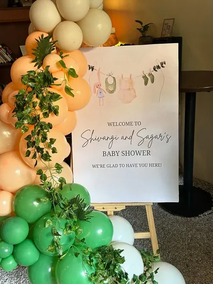 A warm welcome to the tropical baby shower, with a custom sign and a vibrant balloon garland adorned with jungle leaves.