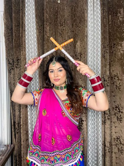 A playful shot with dandiya sticks, showcasing the full Navratri outfit and makeup.