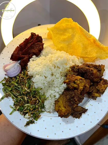 A plate full of variety, including a chicken stir fry, singju salad, crispy pork ribs, and papad.