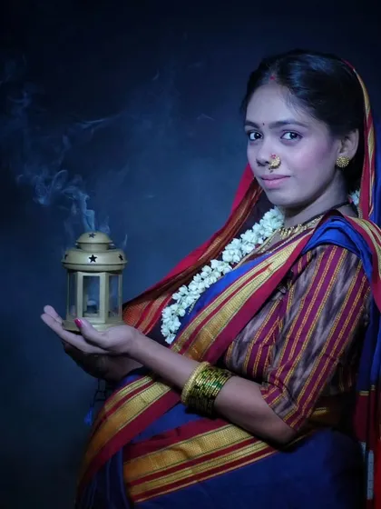 A moody and atmospheric portrait. The traditional Khan saree, the nath, and the gentle smoke from the lantern create a vintage, soulful look that is full of meaning.
