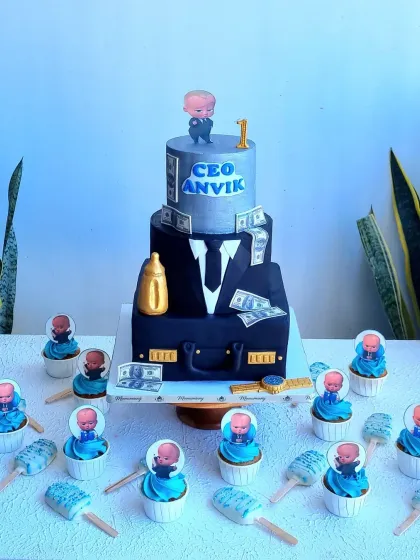 This Boss Baby themed dessert table is perfect for a fun first birthday. It features a three-tier sculpted cake designed as a suit and briefcase, along with matching character cupcakes and cakesicles, creating a complete party setup for your little CEO.
