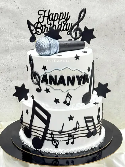 A two-tier birthday cake for a singer. The black and white design is decorated with edible musical notes and a hand-molded microphone.