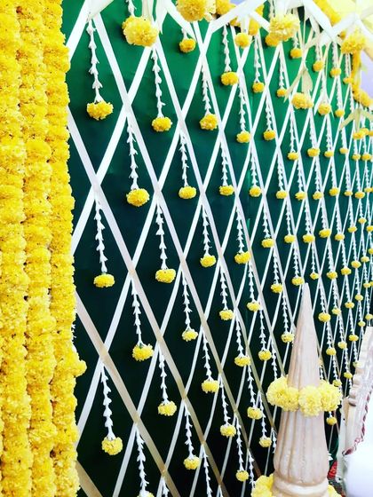 This image shows the layers of a traditional backdrop, with thick garlands of marigolds framing the intricate wall design. The details create a vibrant and authentic setting for the ceremony.