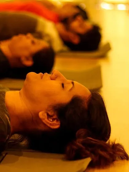 A participant rests deeply during a sound bath, surrounded by the soft light of candles. This is a moment of complete surrender, allowing the body and mind to absorb the healing vibrations.