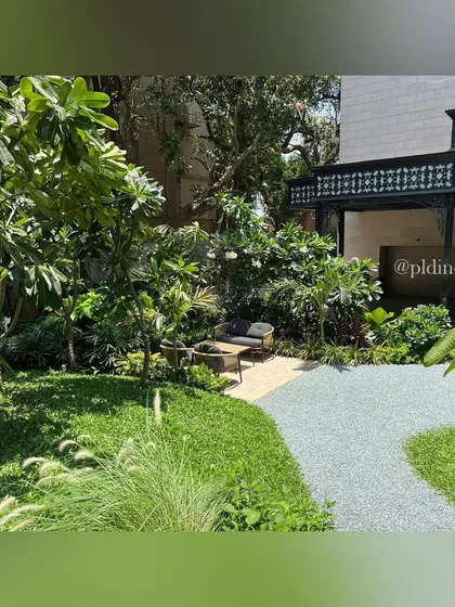 A gravel path winds through a lawn, leading to a secluded seating area. This design creates a sense of journey and discovery within a relatively small garden space.