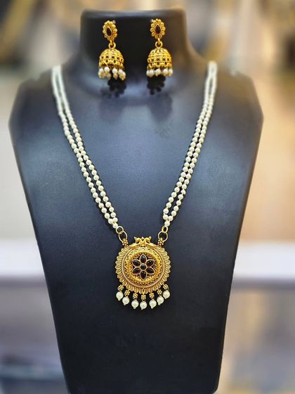 A double pearl chain necklace with a beautiful circular pendant and matching jhumkas.