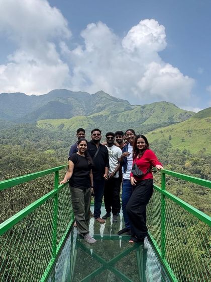 A group posing on the glass bridge in Wayanad, a thrilling experience with a spectacular view of the valley below.