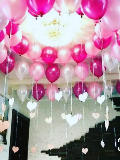 A full ceiling decoration for a welcome baby party. The room is filled with pink, magenta, and white balloons with decorative ribbons and paper hearts hanging down, creating a festive and immersive atmosphere for your celebration.