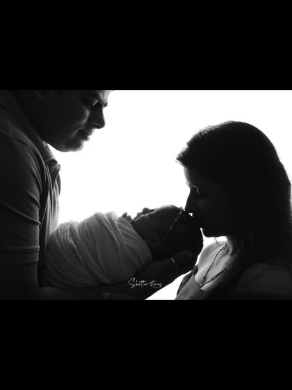 This silhouette composition shows the father holding the baby while the mother leans in to give a gentle kiss.