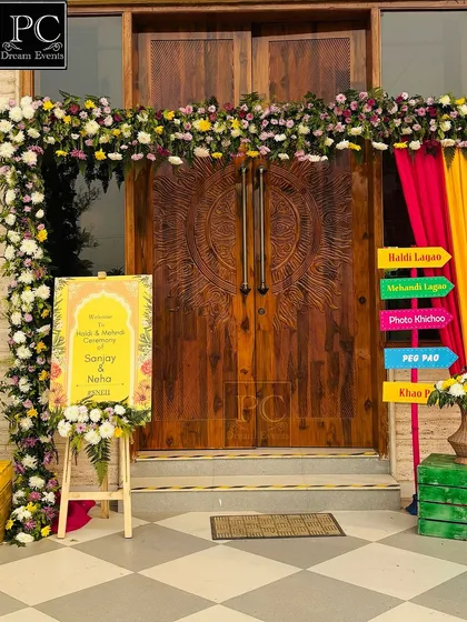 A colorful and festive entrance for a Haldi and Mehndi ceremony. I used a floral arch over a beautiful wooden door and added quirky directional signs for a fun touch.