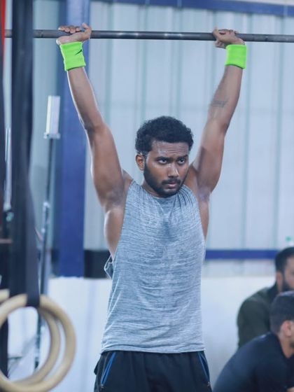 An athlete completes a shoulder-to-overhead lift, demonstrating the upper body strength and stability we build in our training programs.