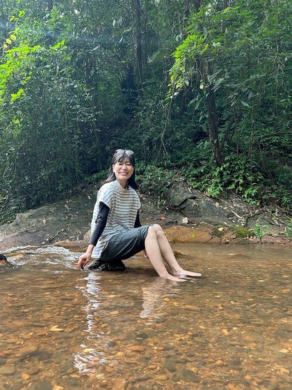 A trekker sitting peacefully in a shallow stream, a perfect way to connect with the natural flow of the forest.
