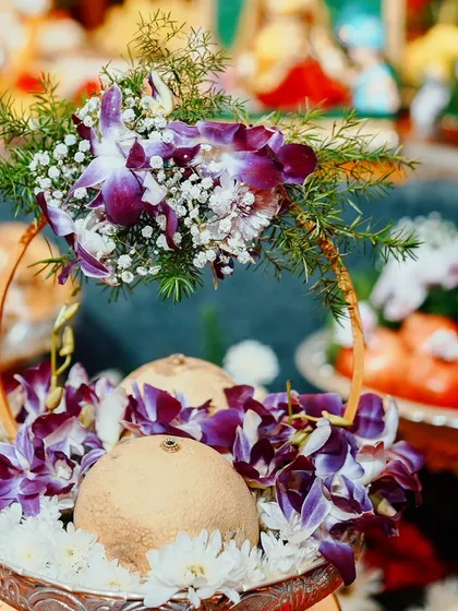 This platter is designed for auspicious offerings, featuring coconuts decorated with beautiful purple orchids and white chrysanthemums. It's perfect for poojas and welcome arrangements.