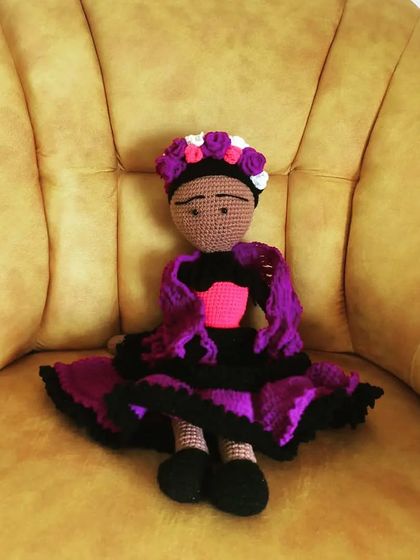 A custom Frida doll in regal purple and black, sitting elegantly on a yellow chair. I can customize the colors of her dress to match your preference.