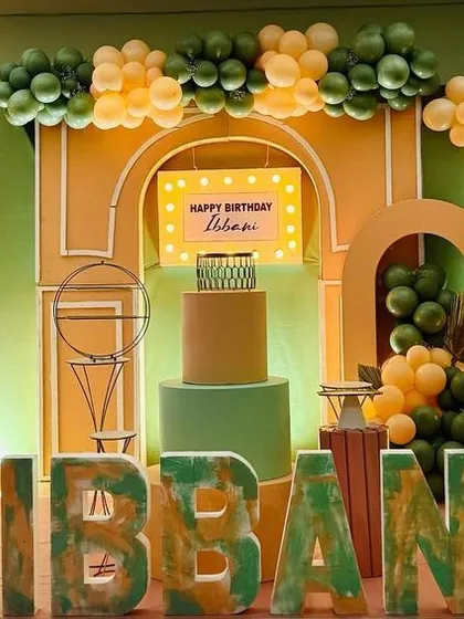 A cheerful and unique party for Ibbani, featuring a pastel green Thomas the Train prop, earthy green and yellow balloons, and custom 3D name lettering.