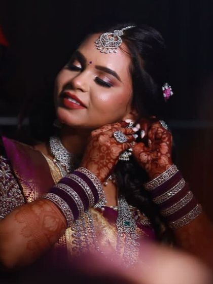 A close-up of the bride getting ready, her mehendi-adorned hands adjusting her earrings.