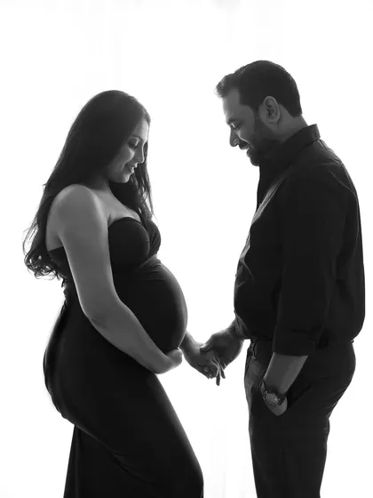 A tender moment between the couple, captured in a timeless black and white silhouette. Their gentle interaction tells a story of love and anticipation.