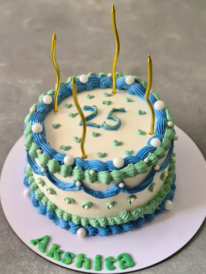 A vintage-style Ferrero Rocher cake for a 25th birthday, with intricate blue and green piping that creates a classic, celebratory feel.