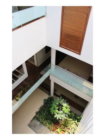 An aerial view into the central courtyard of the 'Boxed In House', a design strategy to overcome the constraints of a narrow urban plot. This vertical void brings light and air into the core of the home, with a glass bridge connecting spaces across the divide.