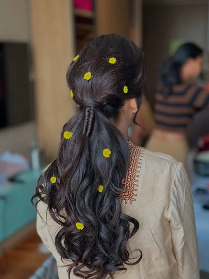 A close-up of the Haldi ponytail with little yellow flowers, showing the delicate braid detail at the base.