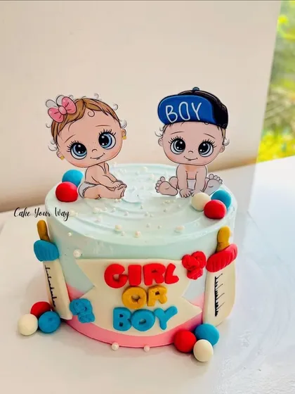 A cute gender reveal cake with adorable baby toppers and milk bottles.