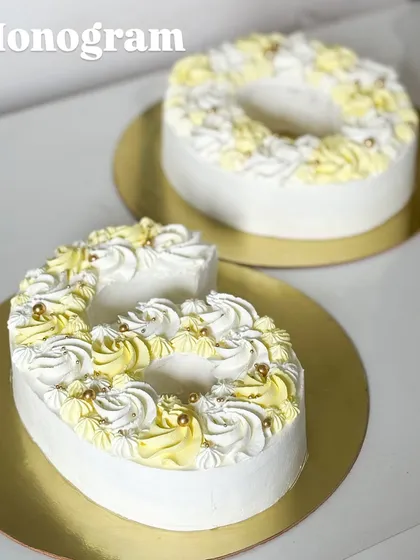 A monogram cake is a perfect way to celebrate a milestone. These "G" and "O" cakes are decorated with beautiful yellow and white piped frosting and delicate gold pearls.