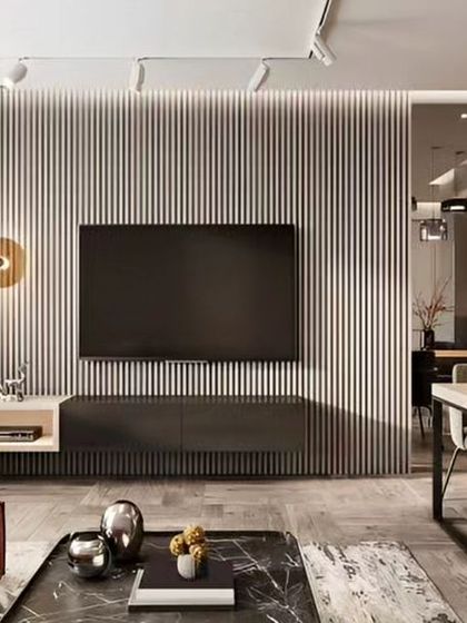 A contemporary open-plan living and dining space. The living area is defined by a grey fluted wall with a minimalist TV console, while the adjacent dining area features elegant modern furniture.