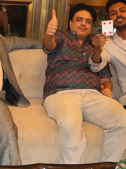 A happy guest gives a thumbs-up after a successful card trick at a house party. It's all about creating those fun, surprising moments for you and your friends.