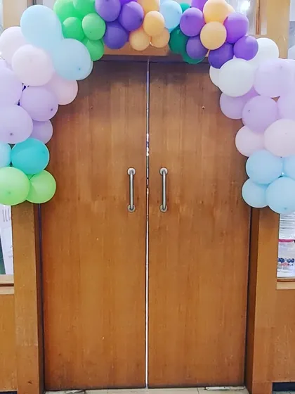 A simple yet effective pastel balloon arch over a wooden door, adding a touch of celebration to the entrance.
