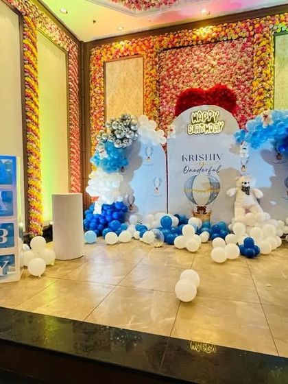 A "Krishiv is Wonderful" themed first birthday with a hot air balloon motif, a photo milestone board, and blue and white balloon decor.