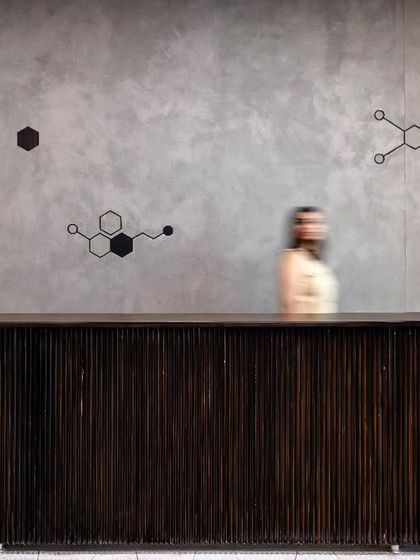 The reception desk at Anthea Pharma, with molecular formulas projected onto the raw concrete wall. This subtle branding element provides an understated reference to the company's pharmaceutical background.