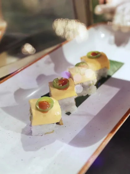 A creative take on sushi, topped with a creamy sauce and a slice of jalapeño for a spicy kick.
