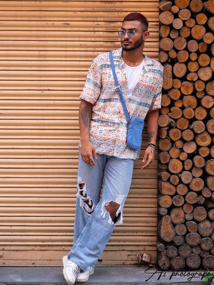 A full-body street style shot showcasing a complete outfit with ripped jeans and a printed shirt. This demonstrates how to style different pieces together for a cohesive look.