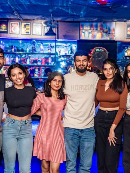 A large group of friends posing in front of the bar.
